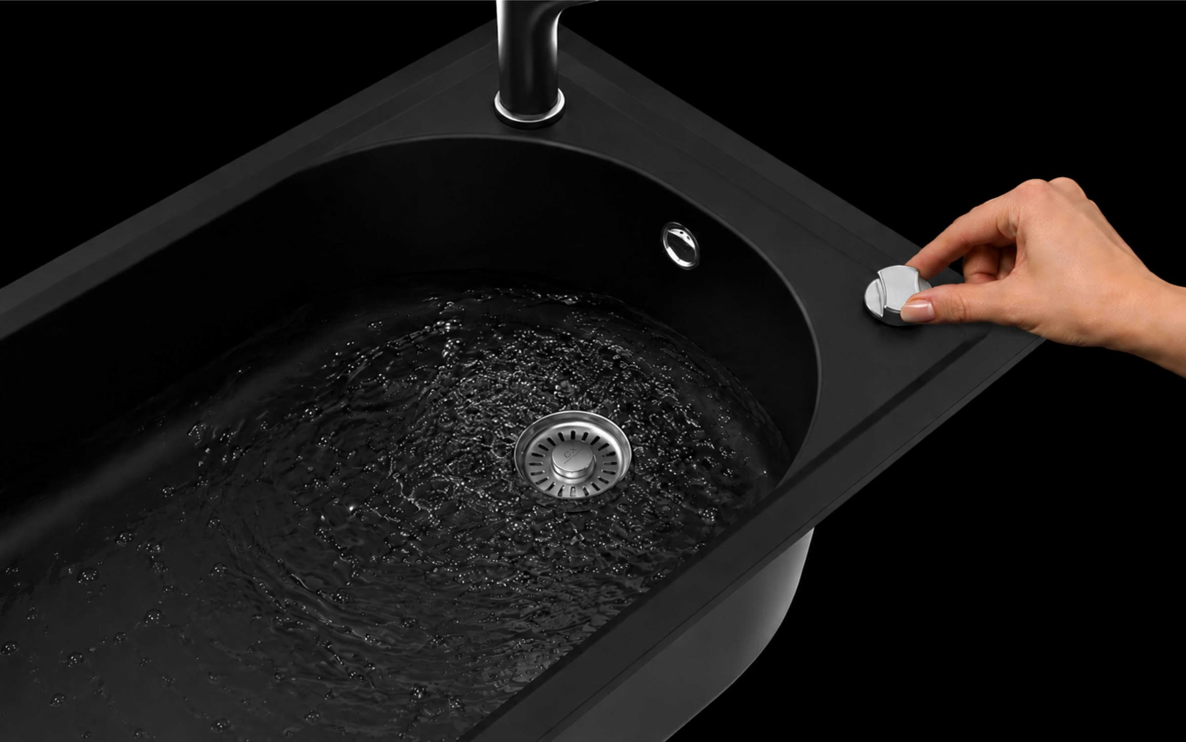 Water swirling over the smooth black Carydura surface of the CX Arch as a hand presses the pop-up drain button