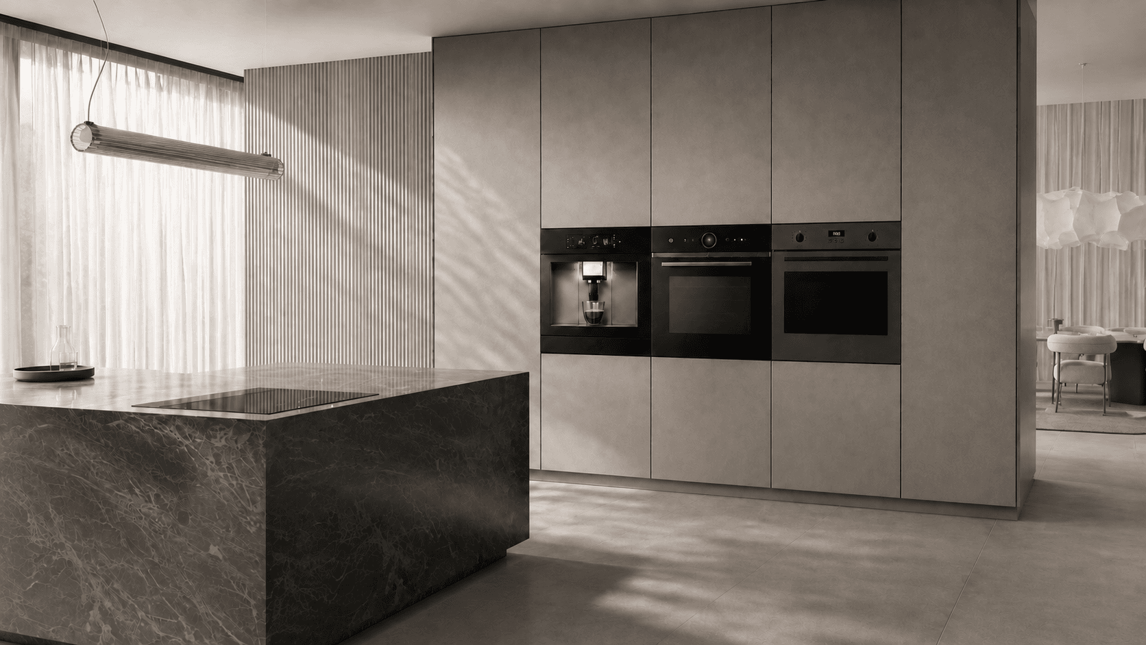 A Carysil built-in coffee machine and two ovens set flush into a kitchen wall, with a dark stone island in the foreground